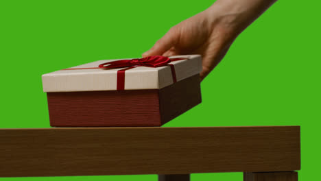 Close-Up-Of-Man-Putting-Down-Gift-Wrapped-Present-Onto-Table-Shot-Against-Green-Screen-1